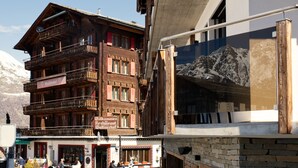 Un edificio de madera de varios pisos con balcones, un letrero que indica un restaurante y vistas a la montaña.