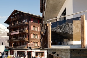 Ein mehrstöckiges Holzgebäude mit Balkonen, einem Schild, das ein Restaurant anzeigt, und Blick auf einen Berg.