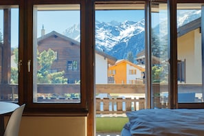 Une piĂšce dotĂ©e dâune grande fenĂȘtre, de meubles en bois et offrant une vue sur les montagnes.