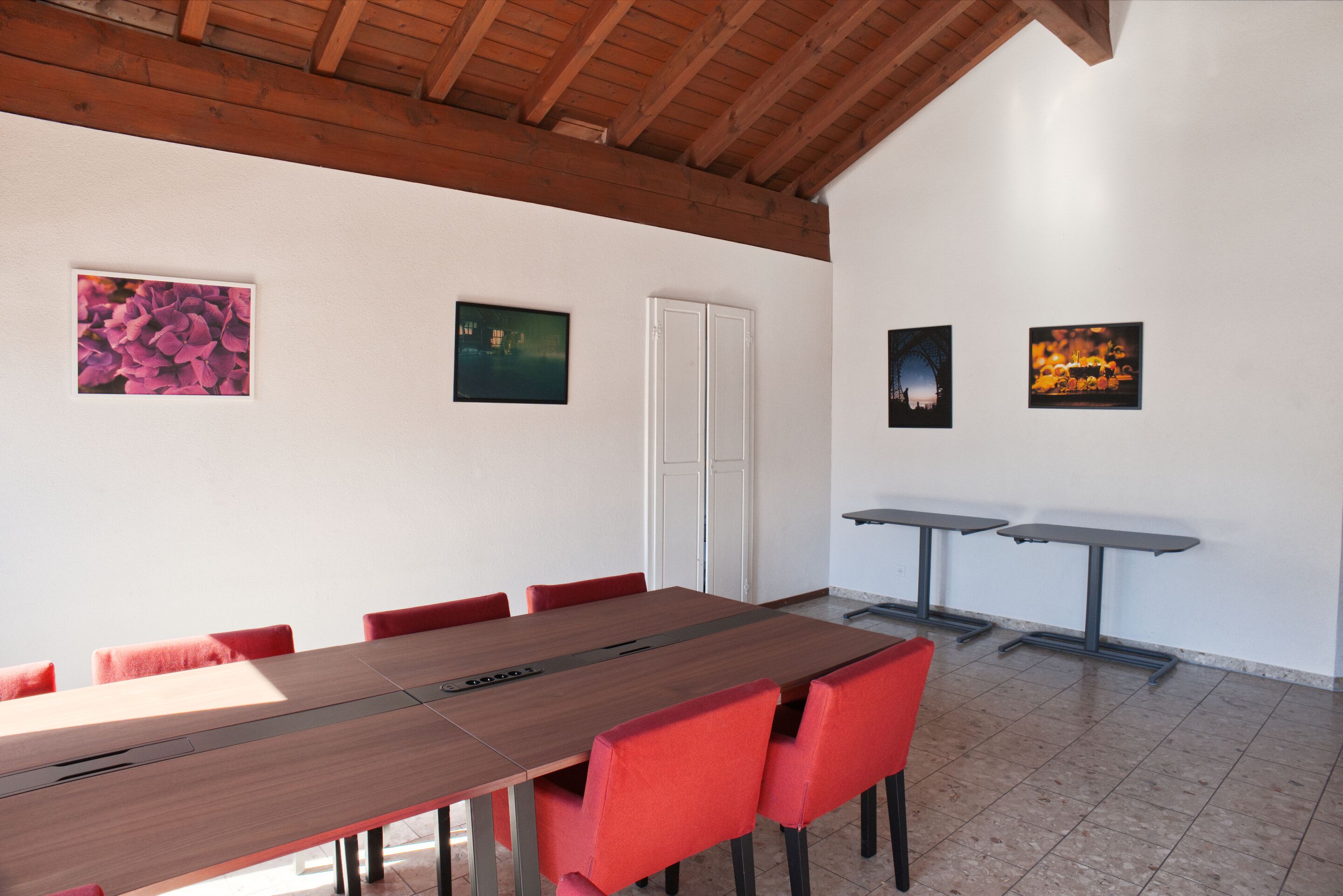 Un salón de conferencias con una larga mesa, sillas rojas y obras de arte en las paredes.