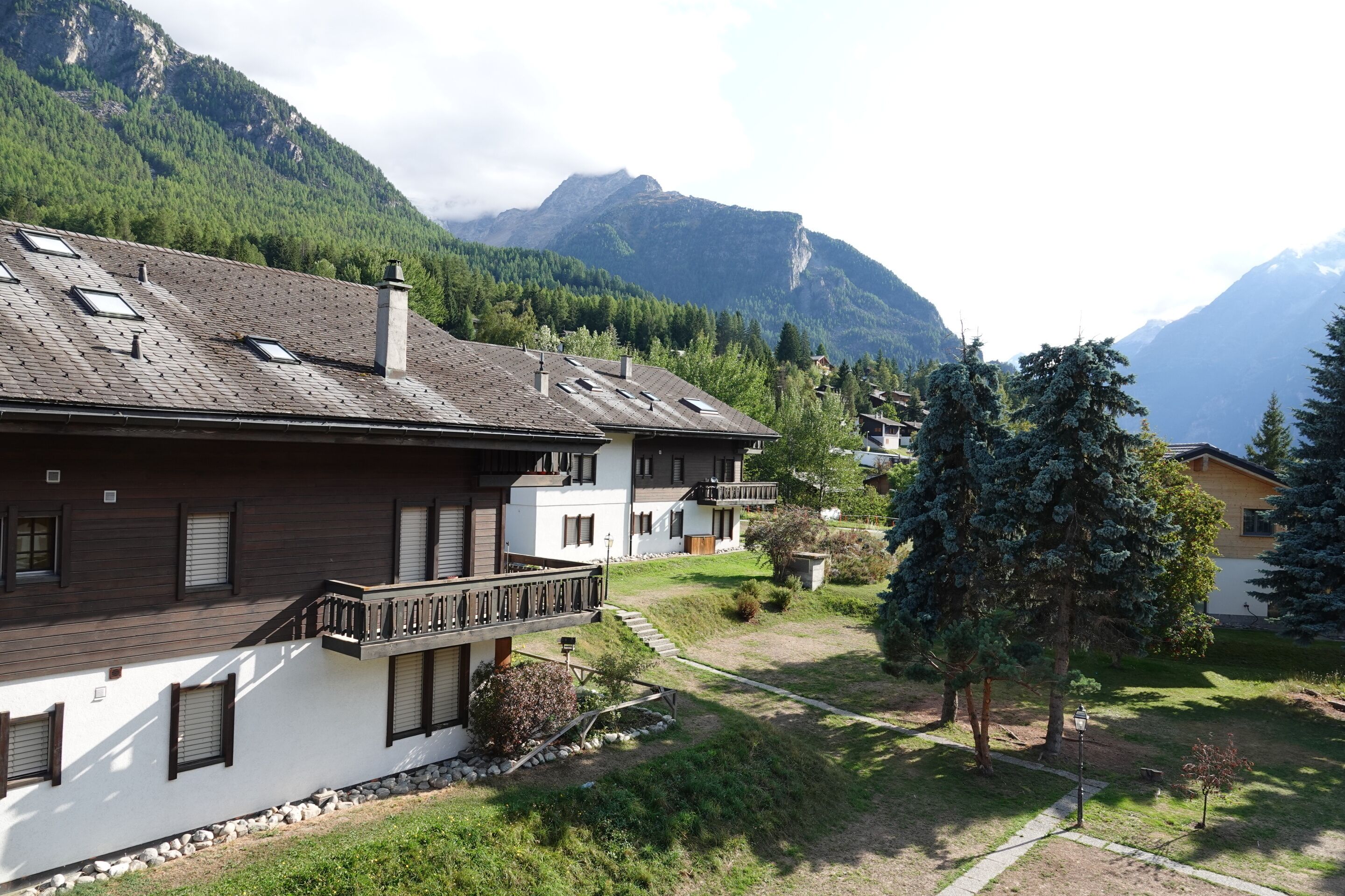 A residential area with houses, a balcony, and a mountain backdrop.