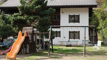 Un parque infantil con tobogán, columpios y una mesa.