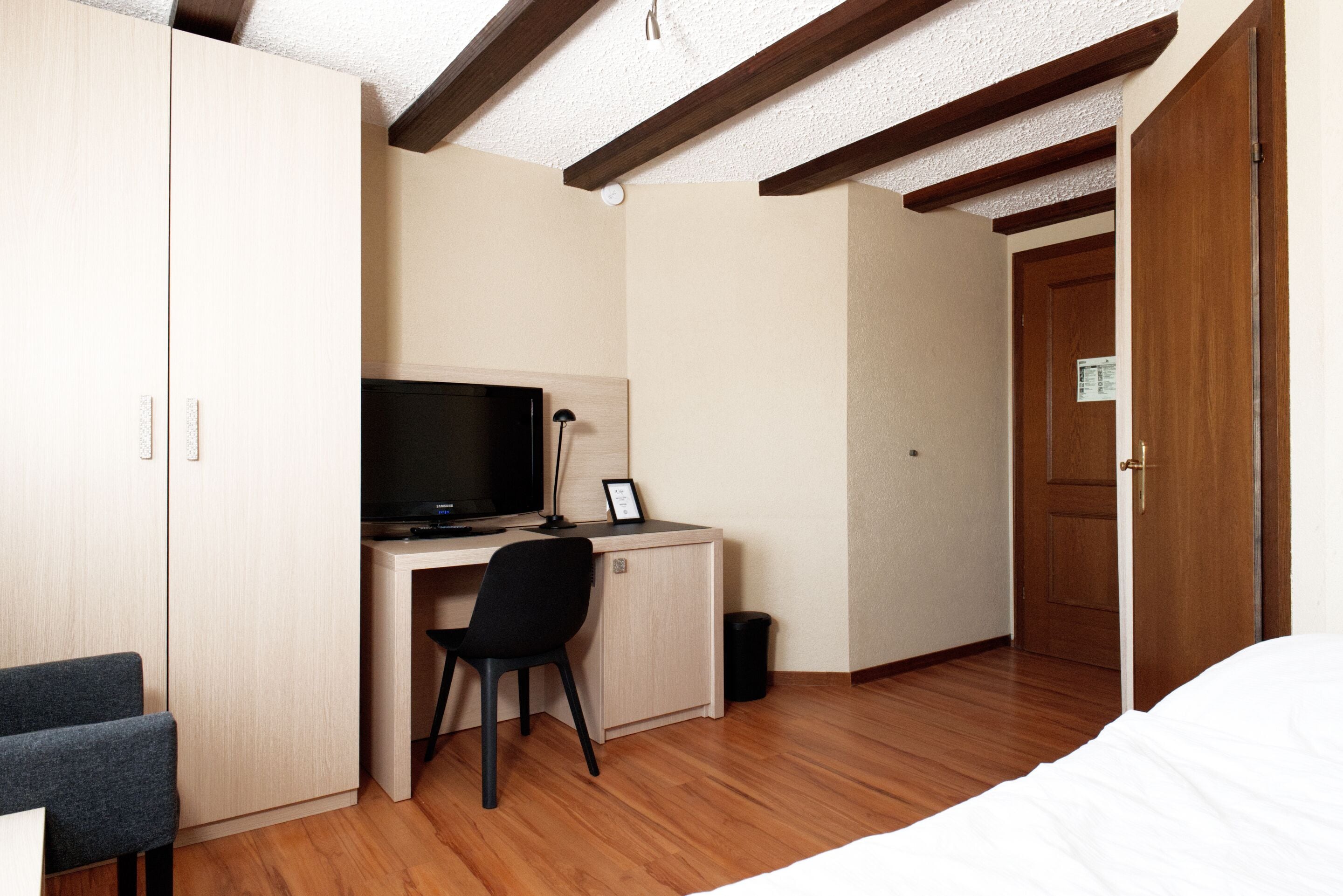 Un dormitorio con una cama, un escritorio con una computadora, una silla y un armario.