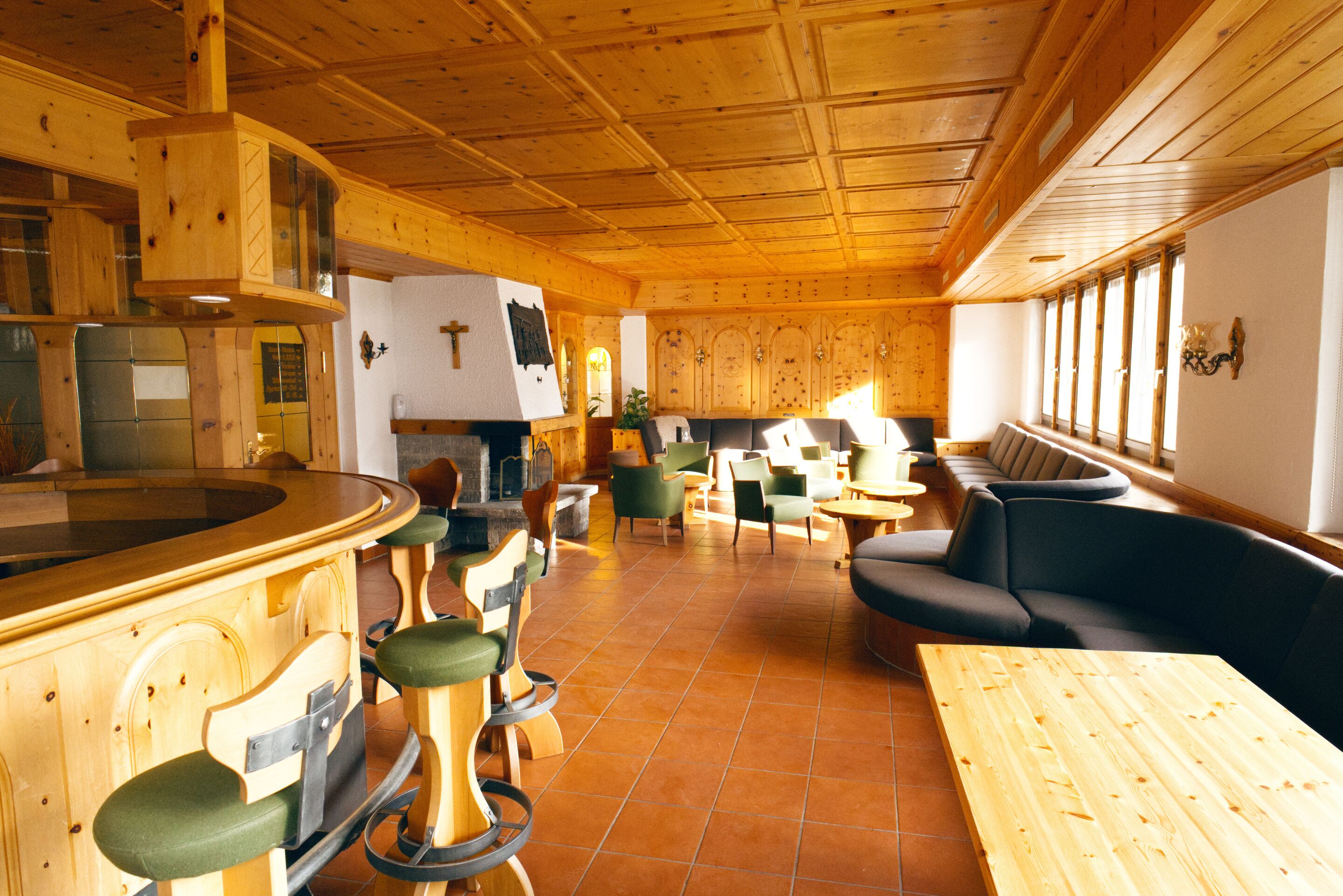A wooden interior with a bar area, seating, and a kitchen.
