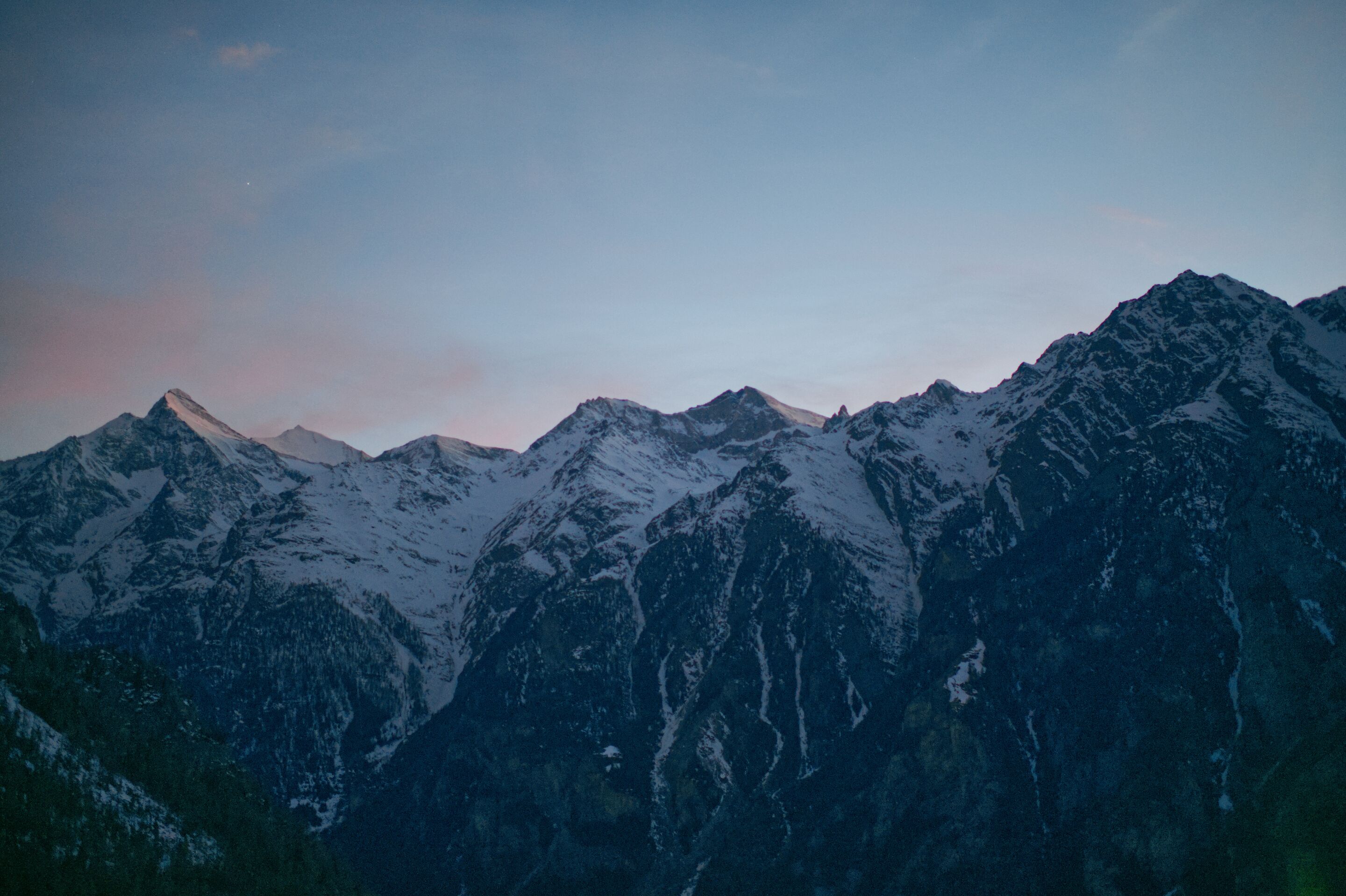 A mountainous landscape with snow-covered peaks and a clear sky.