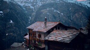 Un pueblo montañoso con casas de madera tradicionales, una iglesia y picos nevados al fondo.