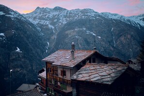 A mountainous village with traditional wooden houses, a church, and snow-capped peaks in the background. - Alpia FlexiHomes (Graechen)