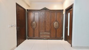 Een hal met een grote houten garderobe, een deur aan de rechterkant en een lichtschakelaar aan de muur.