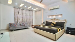 Een slaapkamer met een bed, een slaapbank, een nachtkastje en een airconditioning.