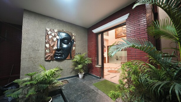 Een modern interieur met een betegelde muur, een groot abstract kunstwerk, potplanten en een bakstenen gevel.