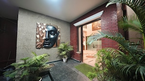 Un interior moderno con una pared de azulejos, una gran obra de arte abstracta, plantas en macetas y fachada de ladrillo.