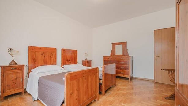 Une chambre à coucher avec deux lits en bois, une commode en bois, un miroir et une armoire.