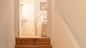 Eine Holztreppe führt zu einem Schlafzimmer mit einem Bett und einem Nachttisch.