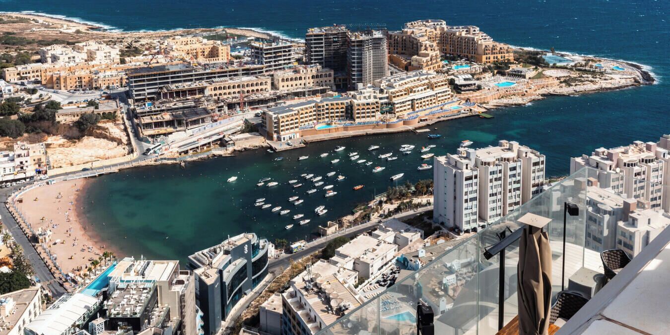 A coastal cityscape with a marina, high-rise buildings, and a beach.