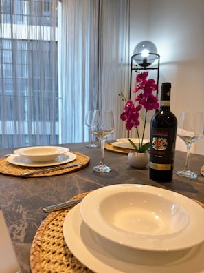 A dining table set with white plates, two wine glasses, and a bottle of Chianti wine. - Cozy Mercury Tower w/RooftopPool by ArcoCollection (St. Julian`s)