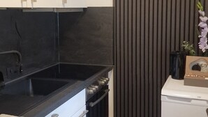Moderni keittiö, jossa on valkoiset kaapit, musta työtaso ja sisäänrakennettu uuni.