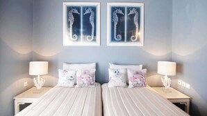 A double bed with white bedding and decorative pillows, two framed seahorse artworks on the wall, and bedside lamps on either side. - Porto Cheli 4Bedroom Villa Plunge Pool & SeaView 2 (Kosta)