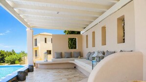 A covered outdoor seating area with a pool, a white sofa, and a metal table. - Porto Cheli 4Bedroom Villa Plunge Pool & SeaView 1 (Kosta)