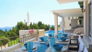 A dining area with a table set for six, outdoor seating, and a view of the sea. - Porto Cheli 4Bedroom Villa Plunge Pool & SeaView 1 (Kosta)