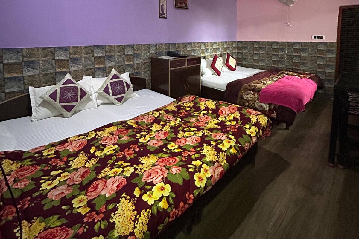 Una habitación con cama, mesita de noche, cómoda, ventilador de techo y calentador de pared.