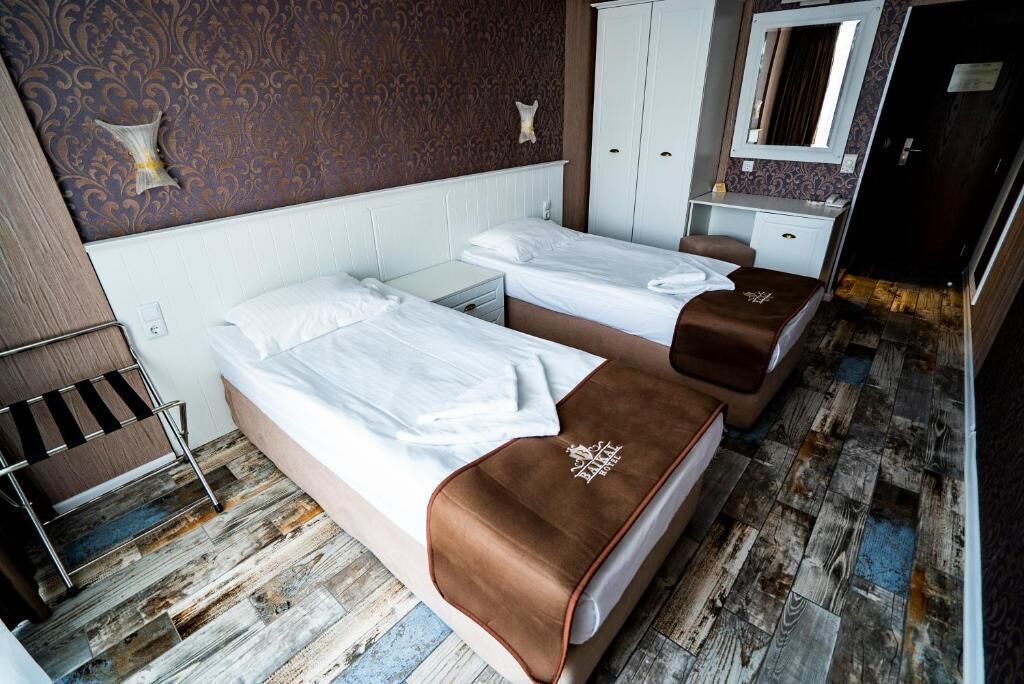 A room with two beds, a wardrobe, a mirror, and a wooden floor.
