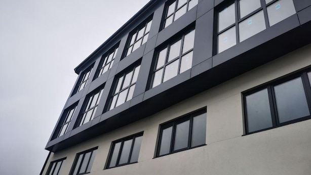 Un edificio de varios pisos con un diseño arquitectónico moderno, que cuenta con una serie de ventanas y un techo plano.