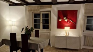 A dining area with a table and chairs, a potted plant, and a red abstract painting on the wall. - 2-BEDROOM LOFT WITH PETITE VENISE RIVER VIEW PRIVATE PARKING (Colmar)