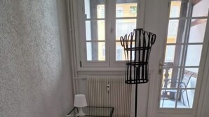 A room with a bed, a small table with a lamp, a radiator, and a window with a view of the outside. - 2-BEDROOM LOFT WITH PETITE VENISE RIVER VIEW PRIVATE PARKING (Colmar)