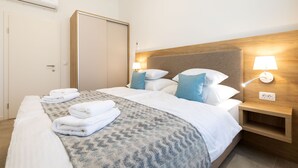Hotellihuone, jossa on sänky, yöpöytä lampun kanssa, vaatekaappi ja ilmastointilaite.
