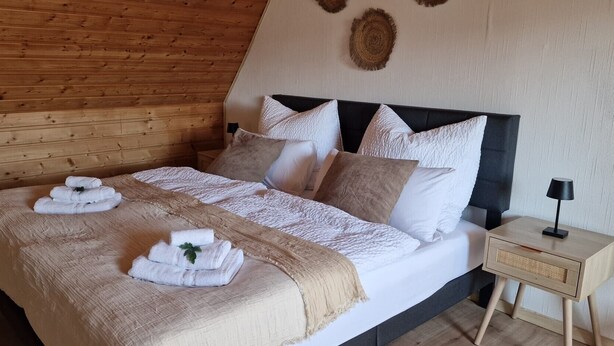 A wooden-paneled room with a bed, pillows, a bedside table, and a wall-mounted decor piece. - Holiday Home 'M B Homes Albstadt' with Mountain View, Private Terrace, Wi-Fi & Single Room (Albstadt)