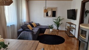 A modern living room with a sofa, a coffee table, a TV, and a fireplace. - Holiday Home 'M B Homes Albstadt' with Mountain View, Private Terrace, Wi-Fi & Single Room (Albstadt)
