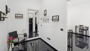 Un interior moderno con comedor, una zona de estar con una silla y un jarrón, y un pasillo que conduce a otra habitación.
