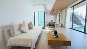 Een moderne woonkamer met een bank, salontafel en uitzicht op een trap die naar een balkon leidt.