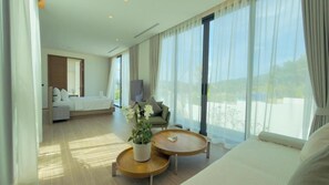 Een moderne hotelkamer met een groot bed, een bank, een salontafel en uitzicht op het omliggende landschap.