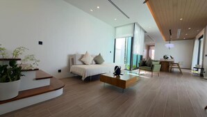 A modern living room with a sofa, coffee table, and staircase. - Phuvista Villas Naithon - Escape Villas  (Sa Khu)