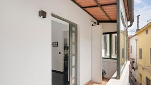 A narrow corridor with a door leading to a room with a tiled floor and a window.