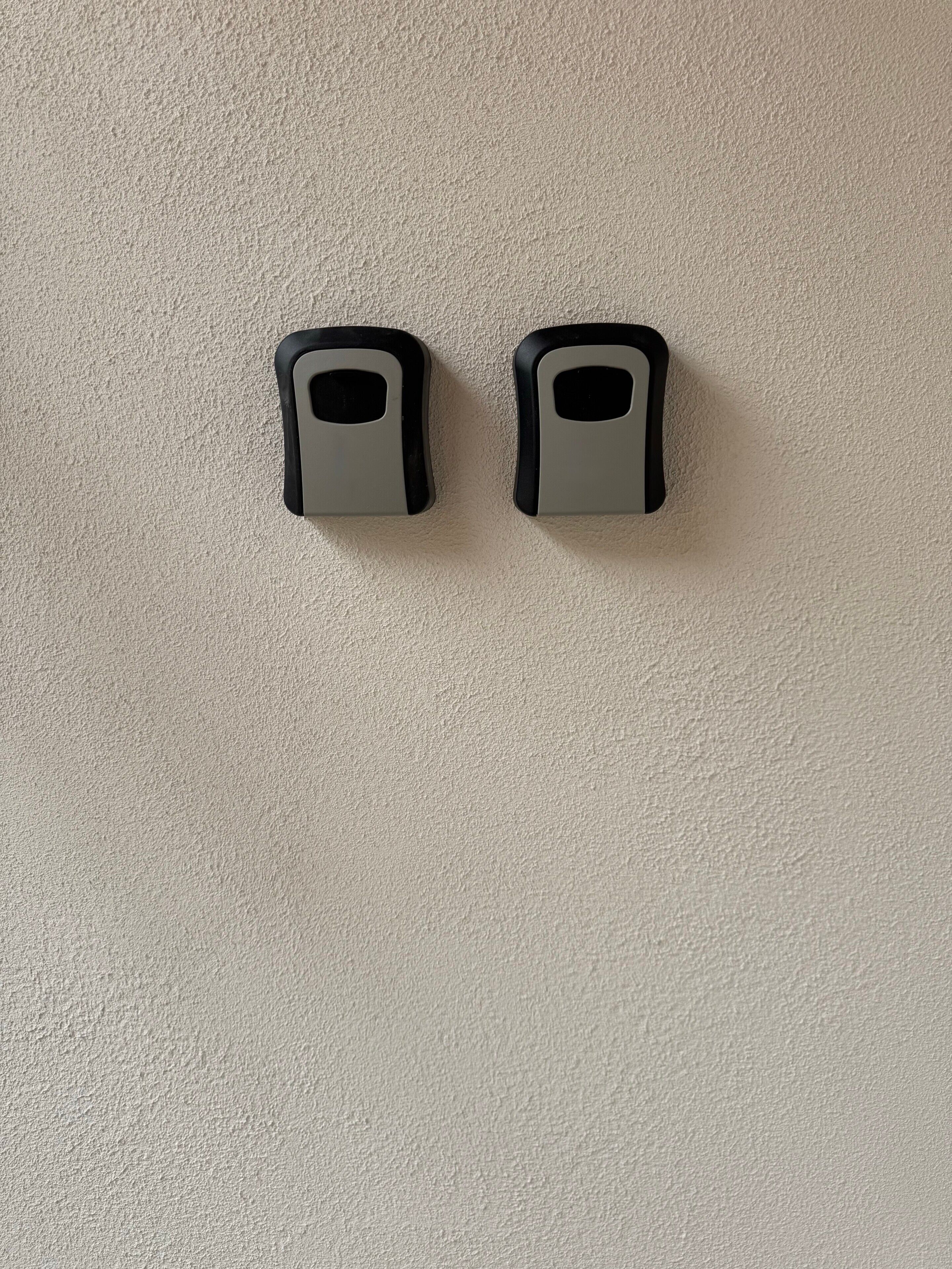 Deux objets fixés au mur, qui pourraient être des poignées de porte, sur un mur à texture.