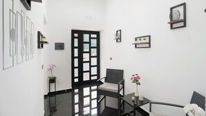 A modern interior with a black-framed chair, a small table with a vase, and a decorative wall panel.