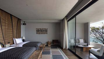 A modern hotel room with a large bed, a sofa, a small table, and a balcony with a view.