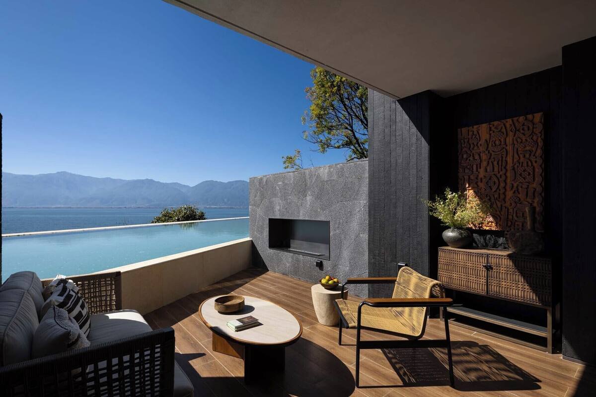A modern outdoor seating area with a pool, a flat-screen TV, and a view of the sea.