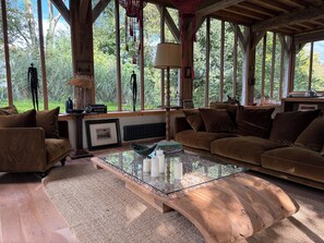 Una sala de estar acogedora con un ventanal grande, una mesa de centro de vidrio y un sofá marrón.