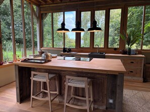 Una cocina con una isla grande, taburetes de bar de madera, un fregadero y lámparas colgantes.