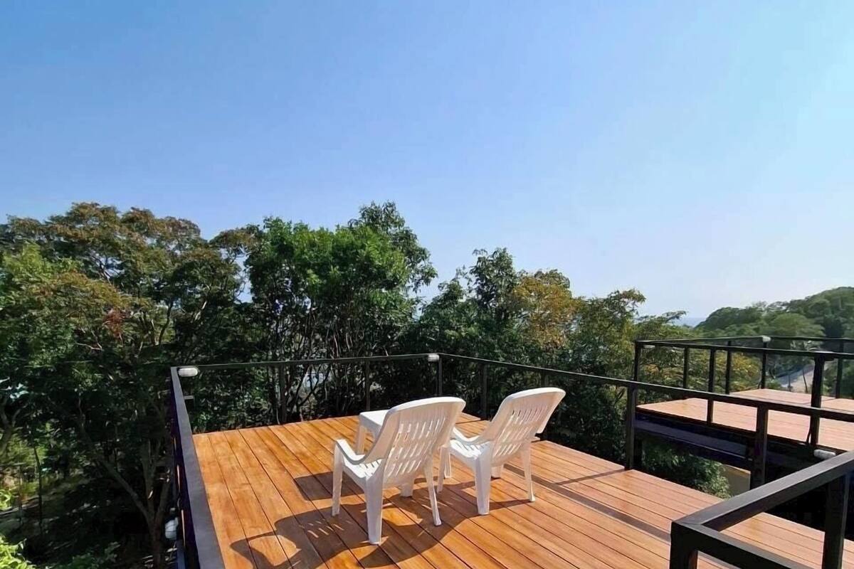 Una terraza de madera con dos sillas de plástico blanco y una barandilla de metal.