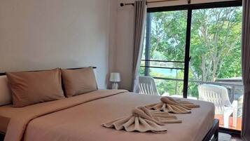 A bedroom with a large bed, a window with curtains, a balcony with chairs, and a ceiling with exposed beams.