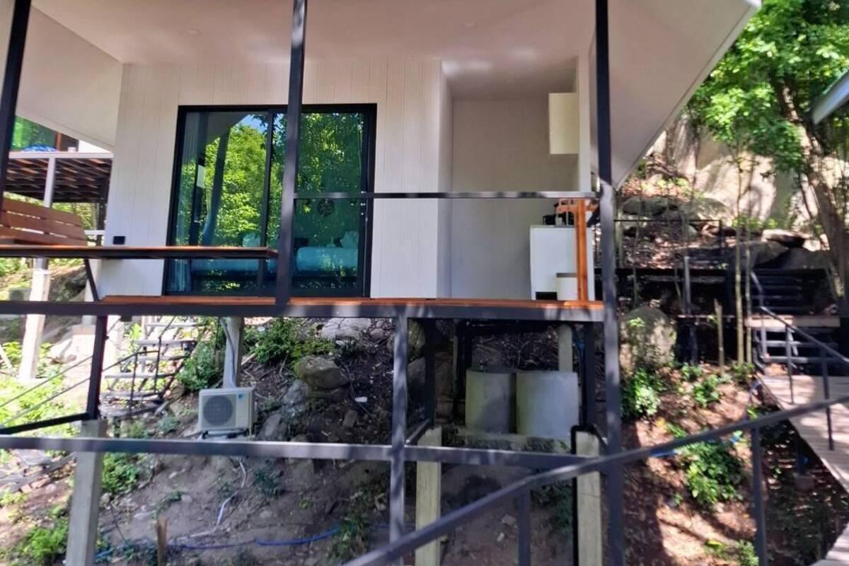 Un edificio moderno con un balcón, una ventana y vistas de la vegetación circundante.
