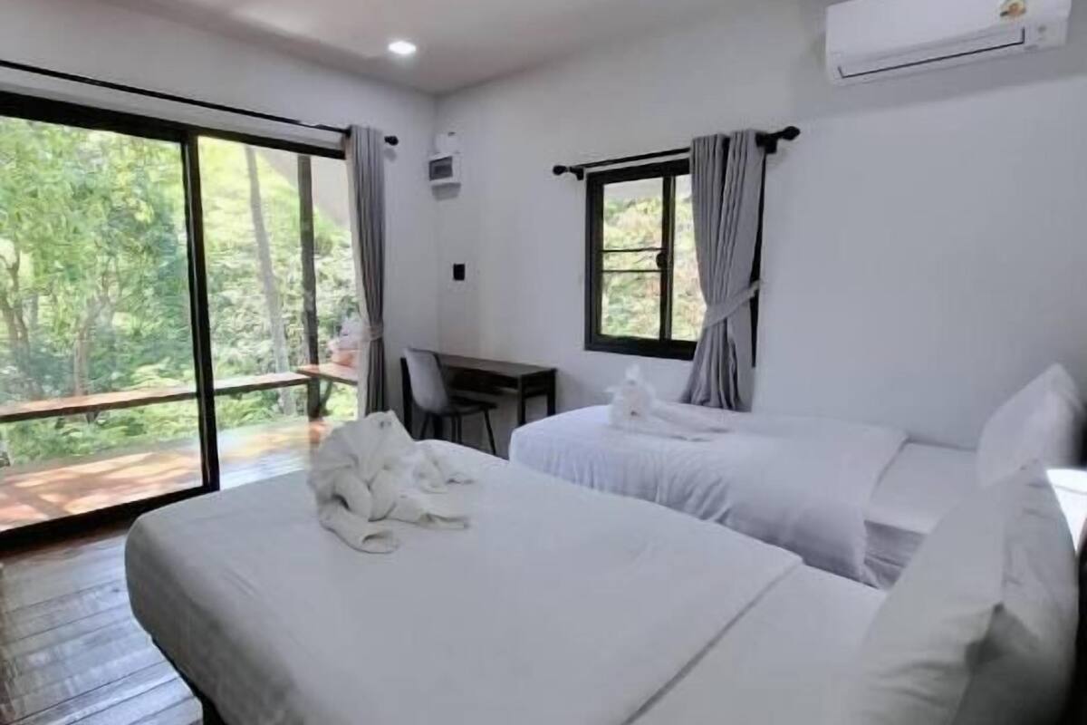 Una habitación de hotel con dos camas, un escritorio y un ventanal grande.