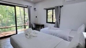 Une chambre d’hôtel avec deux lits, un bureau et une grande fenêtre.