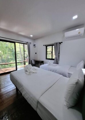 Una habitación de hotel con dos camas, un escritorio y un ventanal grande.