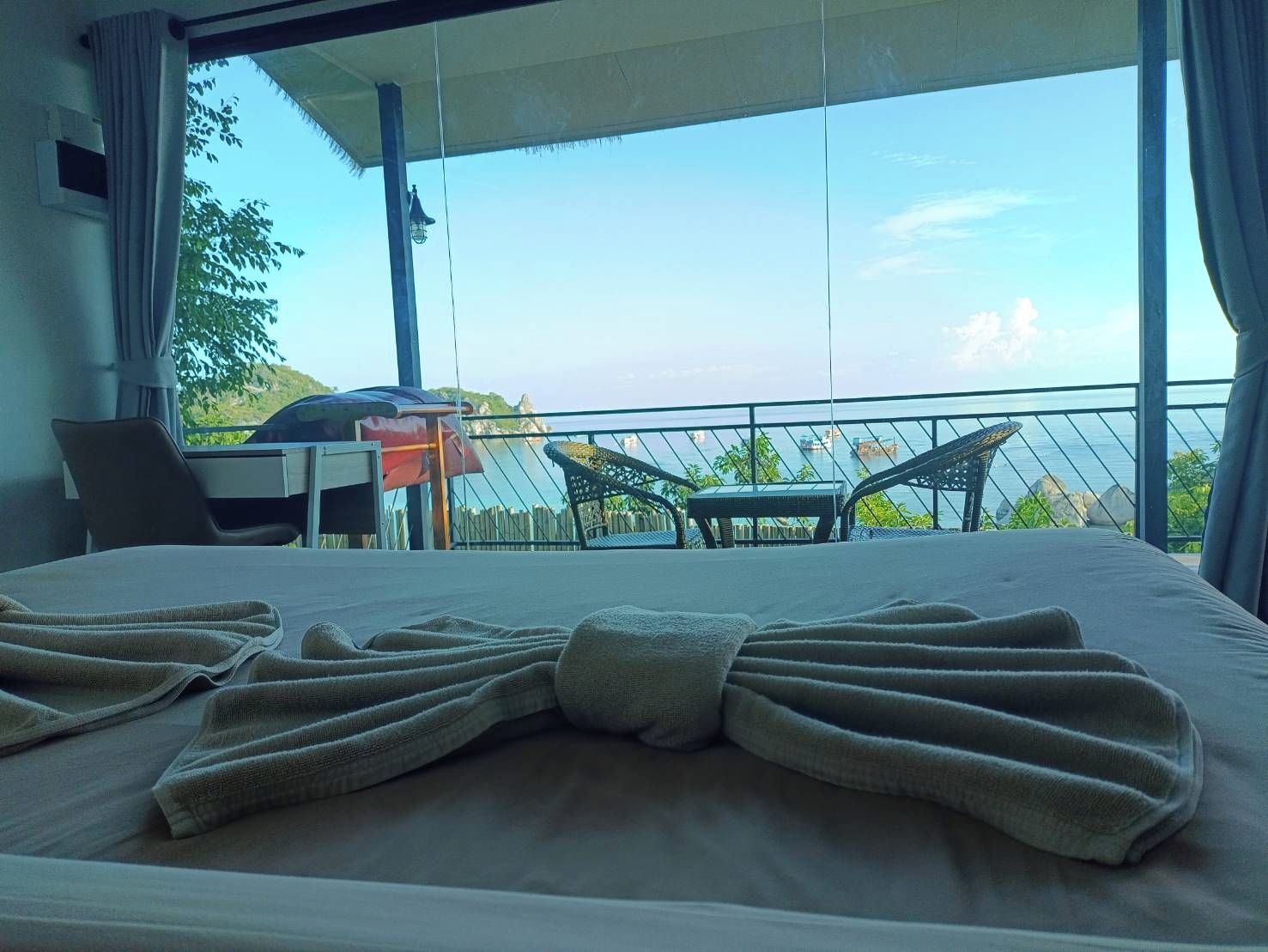 Een hotelkamer met een bed, een stoel, een tafel en uitzicht op zee.