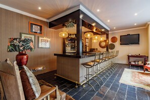 Un espace bar avec un long comptoir, des tabourets de bar et un téléviseur fixé au mur.